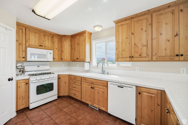 Kitchen featuring white appliances, a sink, and dark tile patterned floors | Image 6
