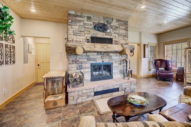 Living area featuring a stone fireplace, wooden ceiling, and recessed lighting | Image 46