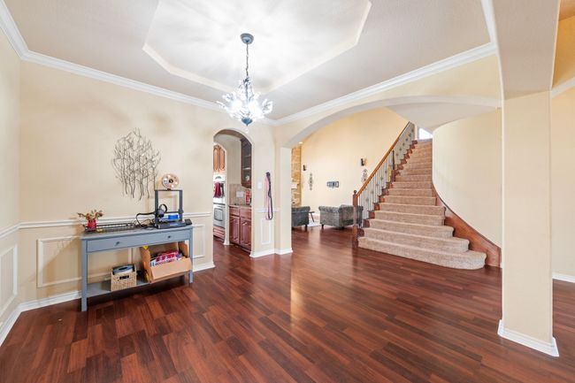 Entryway featuring arched walkways, a decorative wall, dark wood finished floors, a tray ceiling, and stairway | Image 13