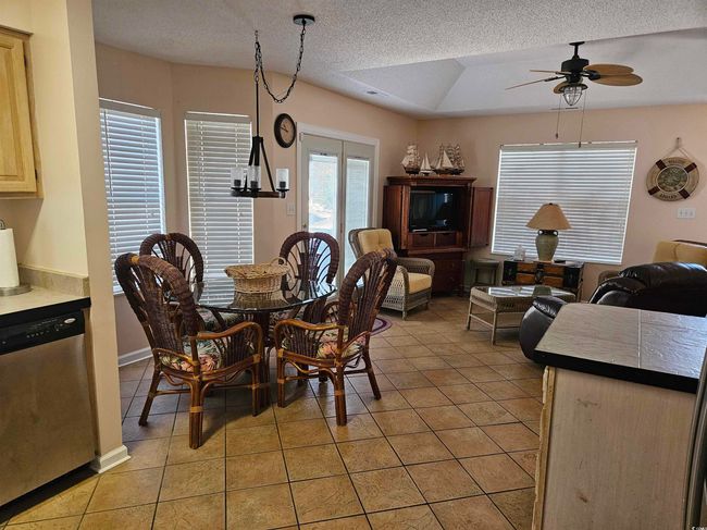 Dining area featuring light tile patterned flooring, ceiling fan, and a textured ceiling | Image 8