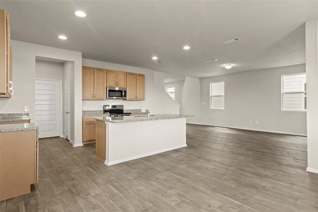 Kitchen with appliances with stainless steel finishes, wood finished floors, recessed lighting, open floor plan, and light stone countertops | Image 15