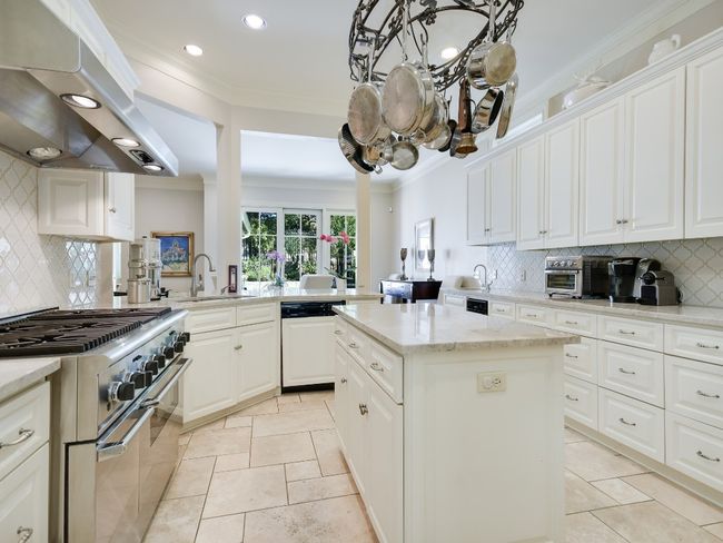 Kitchen with double oven range, dishwashing machine, exhaust hood, a sink, and a chandelier | Image 9