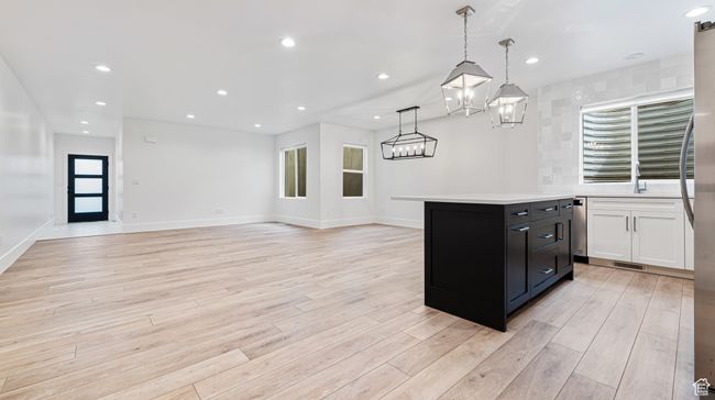 Kitchen with an inviting chandelier, visible vents, light wood finished floors, and light countertops | Image 58