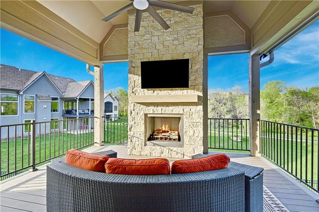 Wooden terrace with an outdoor living space with a fireplace, a lawn, and a ceiling fan | Image 9