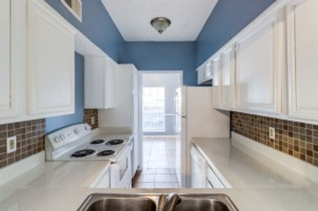 Kitchen with electric range, light countertops, white cabinetry, and decorative backsplash | Image 8