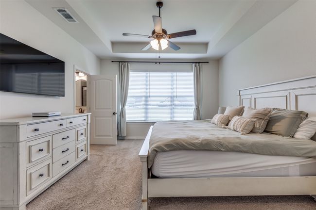 Bedroom with light colored carpet, a tray ceiling, and ceiling fan | Image 15
