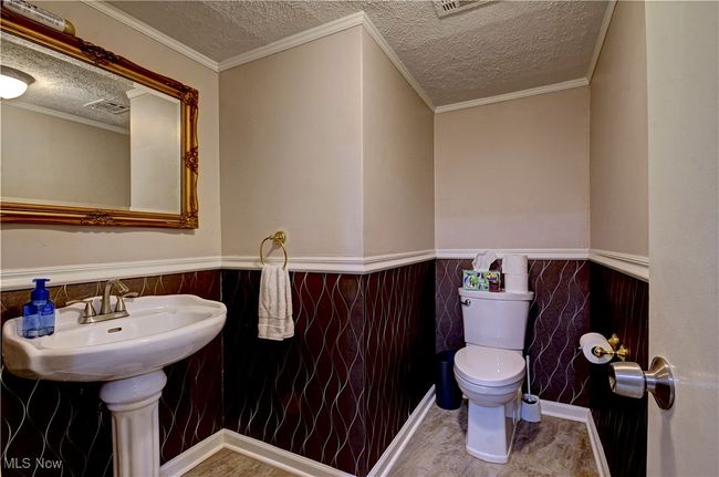 Bathroom with a wainscoted wall, a textured ceiling, wood finished floors, tile walls, and ornamental molding | Image 34