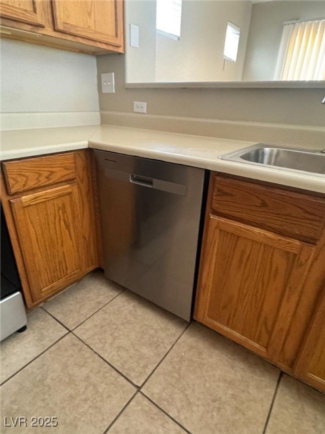 Kitchen with a sink, light countertops, brown cabinets, and dishwasher | Image 8