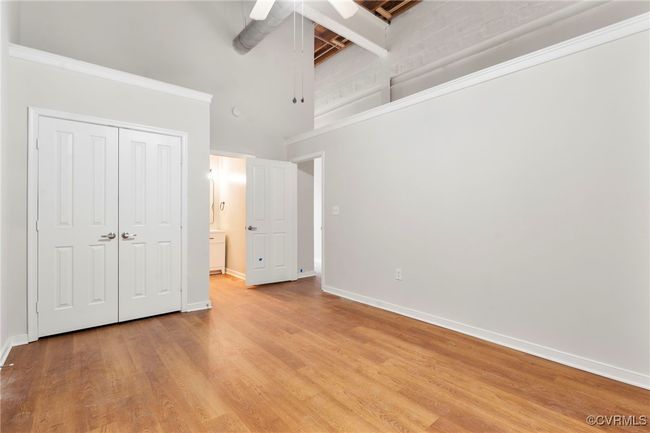 Unfurnished bedroom with a towering ceiling, light wood-style floors, ceiling fan, and a closet | Image 9