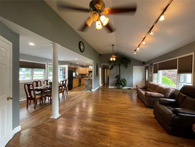 Living area featuring ceiling fan, track lighting, ornate columns, vaulted ceiling, and wood finished floors | Image 9