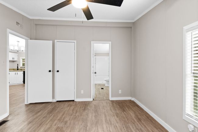 Unfurnished bedroom featuring light wood finished floors, ornamental molding, multiple windows, and connected bathroom | Image 23