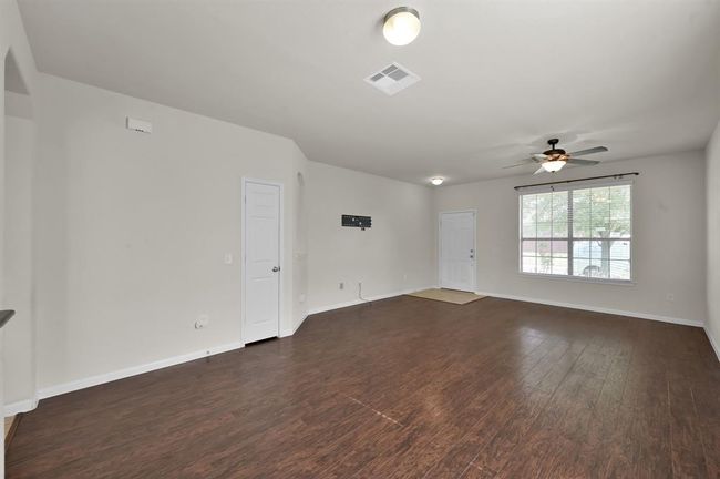 The kitchen features modern appliances, wooden cabinetry, and a central island. The adjoining living space has ample natural light, tile flooring in the kitchen, and wood flooring in the living area, creating a warm and inviting atmosphere. | Image 9