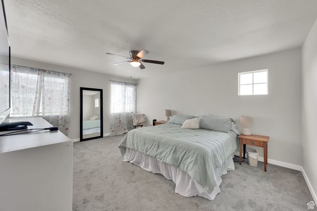 Bedroom featuring multiple windows, light colored carpet, ceiling fan, and a textured ceiling | Image 17
