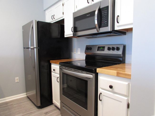 Kitchen featuring butcher block counters, white cabinets and stainless steel appliances. | Image 23