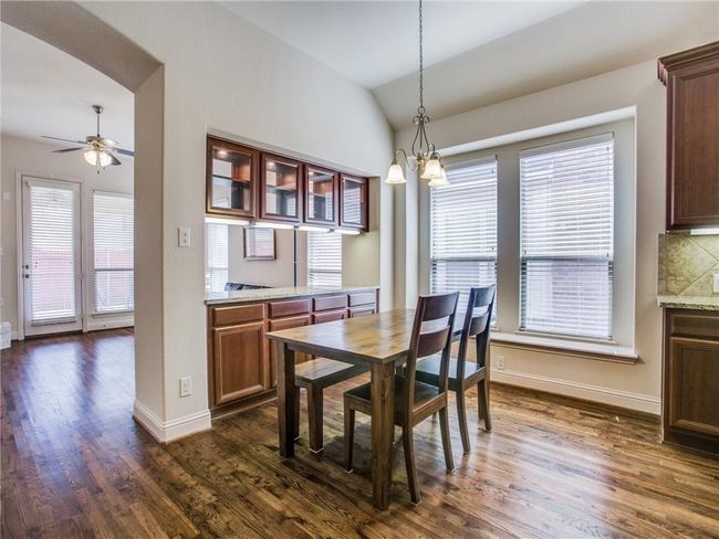 Dining space with lofted ceiling, dark wood-style flooring, ceiling fan, baseboards, and a chandelier | Image 9