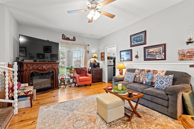Living area featuring ceiling fan, wood finished floors, and a glass covered fireplace | Image 7