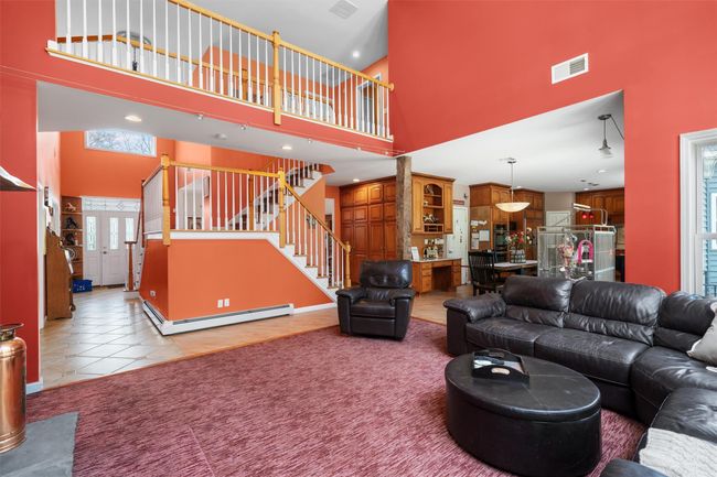 Living room featuring visible vents, a high ceiling, stairway, tile patterned floors, and a baseboard heating unit | Image 14