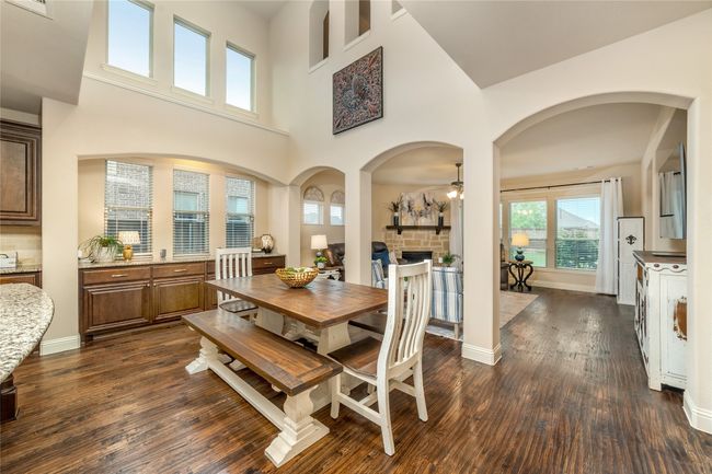 Dining room with dark wood-type flooring, ceiling fan, a fireplace, a high ceiling, and baseboards | Image 7