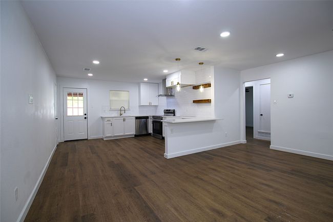 Kitchen with dark wood finished floors, light countertops, baseboards, a peninsula, and appliances with stainless steel finishes | Image 5