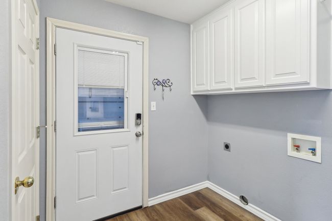 Laundry area featuring dark wood-style flooring, washer hookup, baseboards, electric dryer hookup, and cabinet space | Image 18