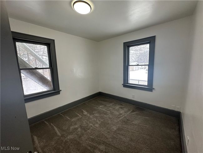 Spare room featuring dark colored carpet, plenty of natural light, and baseboards | Image 27