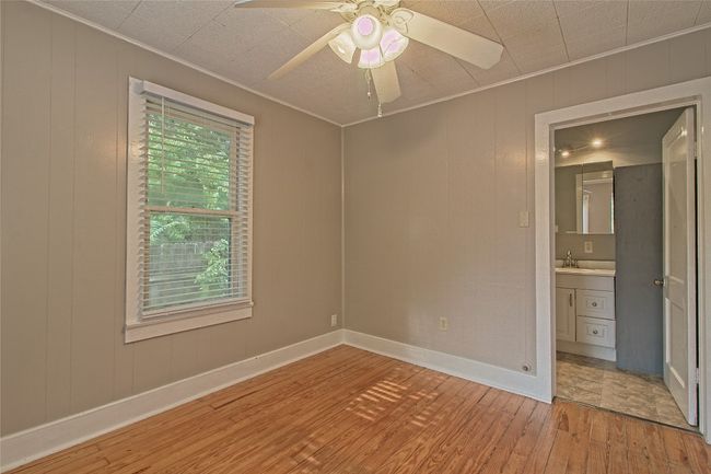 Empty room featuring light wood-type flooring, ornamental molding, a ceiling fan, and a decorative wall | Image 22