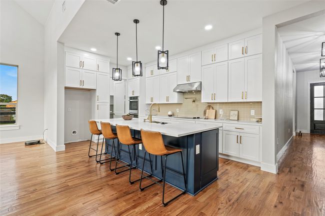 Kitchen featuring under cabinet range hood, white cabinetry, light countertops, backsplash, and recessed lighting | Image 10
