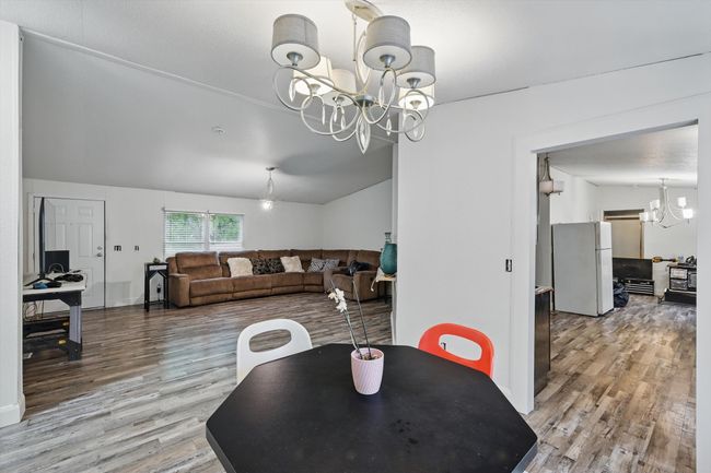 Dining space featuring vaulted ceiling, wood finished floors, and a notable chandelier | Image 9
