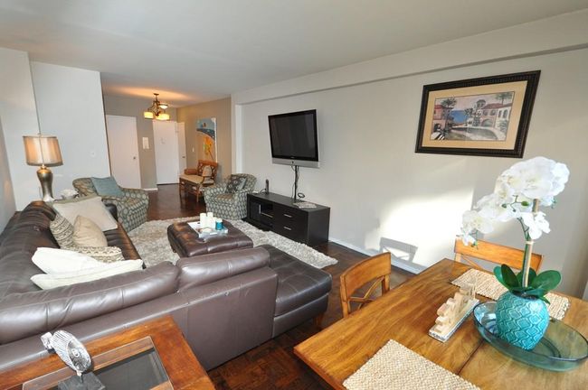 The living room can accommodate a dining and entertainment area and overlooks the North courtyard. The room has parquet floors that extend into the dining foyer. | Image 6