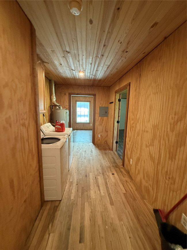 Hall featuring water heater, washing machine and dryer, light wood-type flooring, wooden ceiling, and wood walls | Image 30