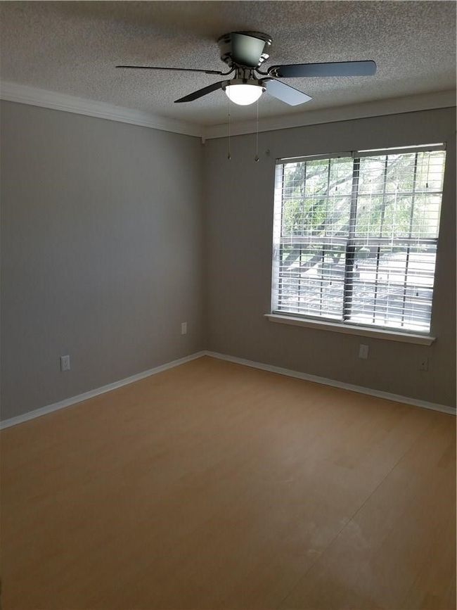 Spare room with a textured ceiling, a ceiling fan, baseboards, ornamental molding, and light wood finished floors | Image 6