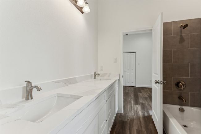 Bathroom featuring wood finished floors, bathing tub / shower combination, and double vanity | Image 23