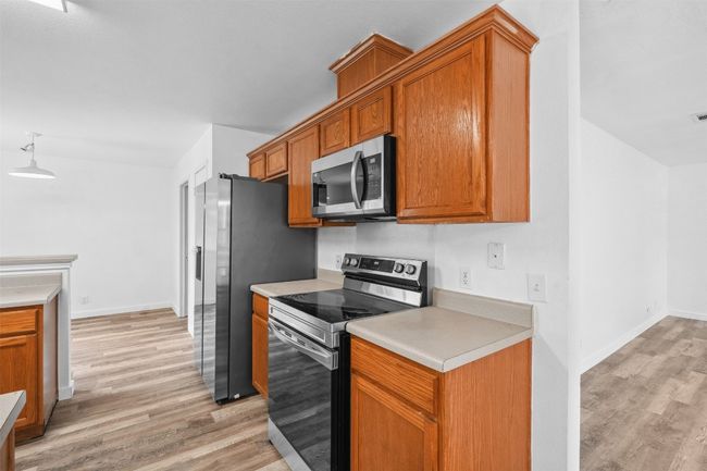 Kitchen with light countertops, stainless steel appliances, baseboards, and light wood-style floors | Image 17