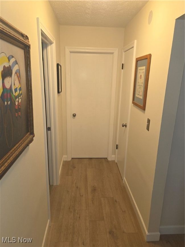 Corridor with baseboards, wood finished floors, and a textured ceiling | Image 23