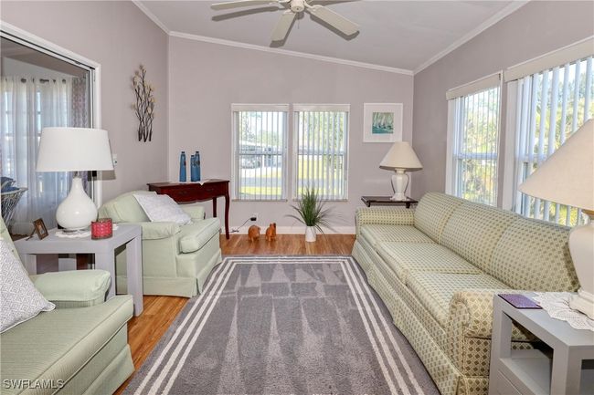 Living room featuring crown molding, hardwood / wood-style floors, a healthy amount of sunlight, and lofted ceiling | Image 20