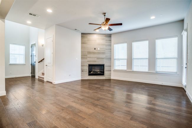 Unfurnished living room featuring ceiling fan, healthy amount of natural light, a tile fireplace, stairway, and recessed lighting | Image 5