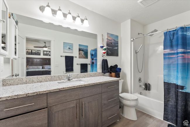 Ensuite bathroom with wood finished floors, a ceiling fan, vanity, shower / bath combination with curtain, and toilet | Image 18