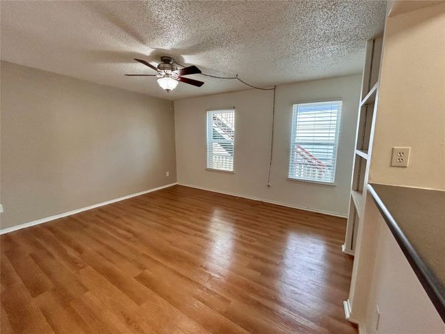 Empty room featuring wood finished floors, a ceiling fan, and a textured ceiling | Image 4