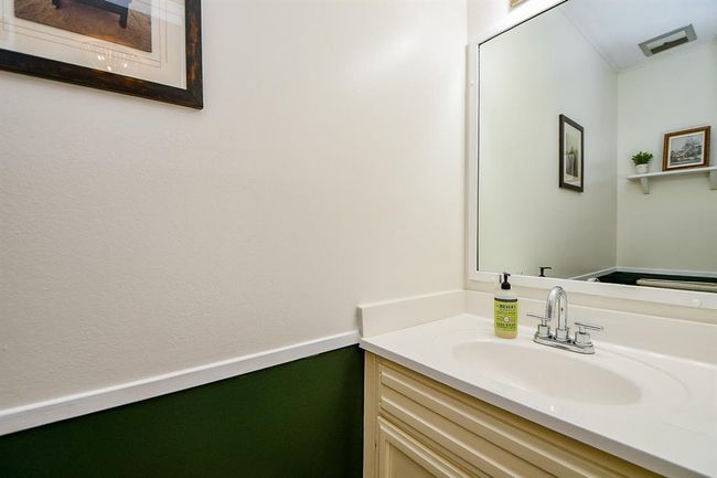 This bathroom features a clean, modern design with a white vanity, a large mirror, and simple decor. The walls are two-toned with a green lower half, adding a touch of color. | Image 40