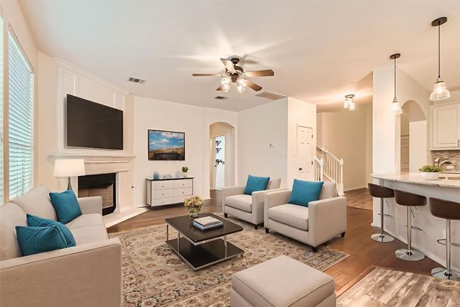 Living room featuring arched walkways, light wood-style flooring, a ceiling fan, and stairs (virtual staging) | Image 4
