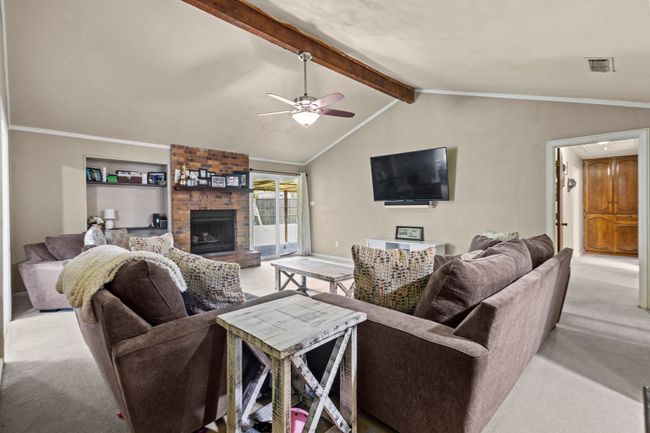Living room featuring light colored carpet, a brick fireplace, and ceiling fan | Image 4