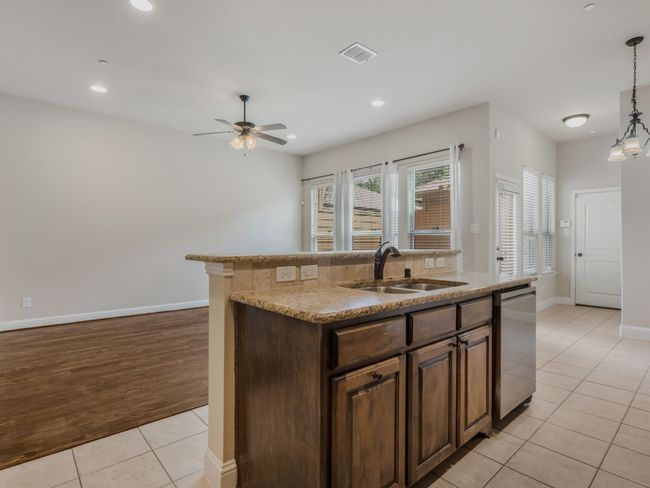 Kitchen with light tile patterned flooring, a center island with sink, recessed lighting, ceiling fan, and decorative light fixtures | Image 18