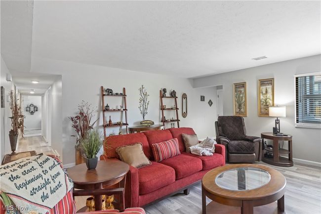 Living area featuring baseboards, visible vents, light wood-type flooring, and a textured ceiling | Image 13