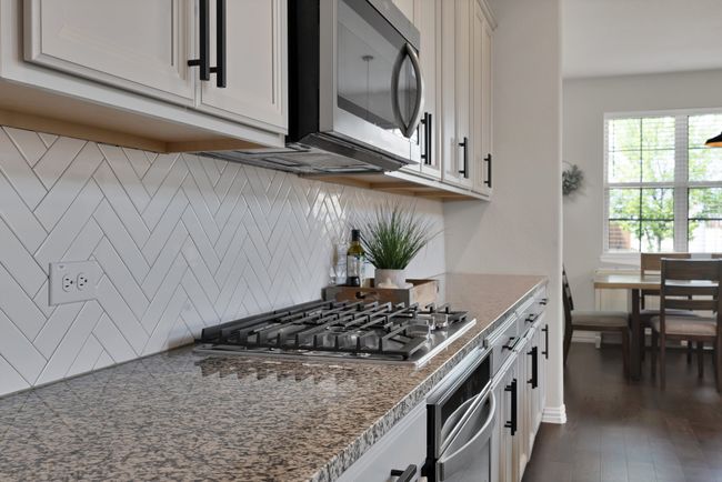 Kitchen with white cabinets, dark wood-style floors, tasteful backsplash, and appliances with stainless steel finishes | Image 15