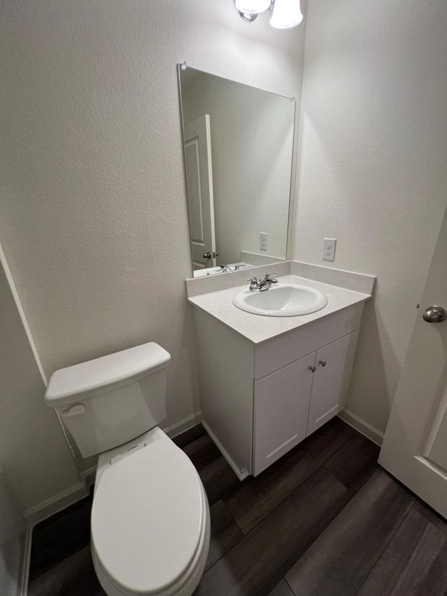 Half bathroom with vanity, toilet, wood finished floors, and baseboards | Image 26