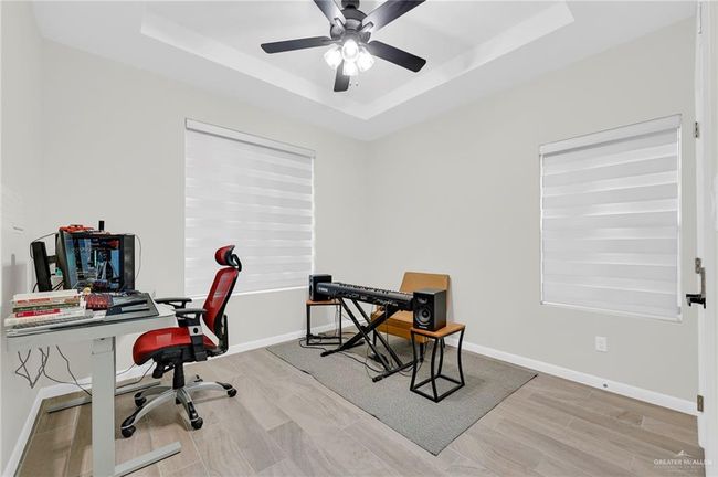 Bedroom featuring light wood-style tile flooring, a raised ceiling, recessed lighting, and baseboards | Image 17
