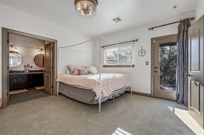 Carpeted bedroom with visible vents, ensuite bathroom, access to outside, a sink, and baseboards | Image 23