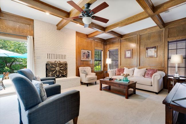 Great room with beamed ceiling, ceiling fan, light colored carpet, and wood walls | Image 10