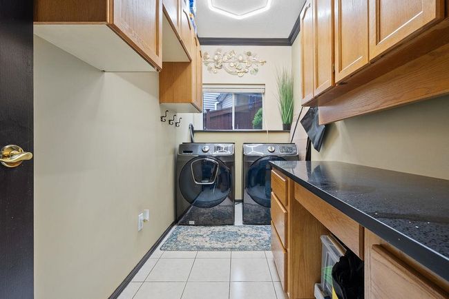 Clothes washing area with washer and clothes dryer, cabinet space, light tile patterned floors, and crown molding | Image 30