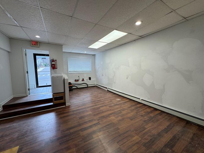 Empty room featuring a paneled ceiling, dark hardwood / wood-style flooring, and a baseboard heating unit | Image 9